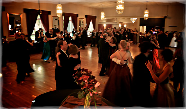 Elegantly-dressed dancers dancing in a posh ballroom.