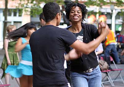 A black couple swing dancing to the band at Dancing til Dusk